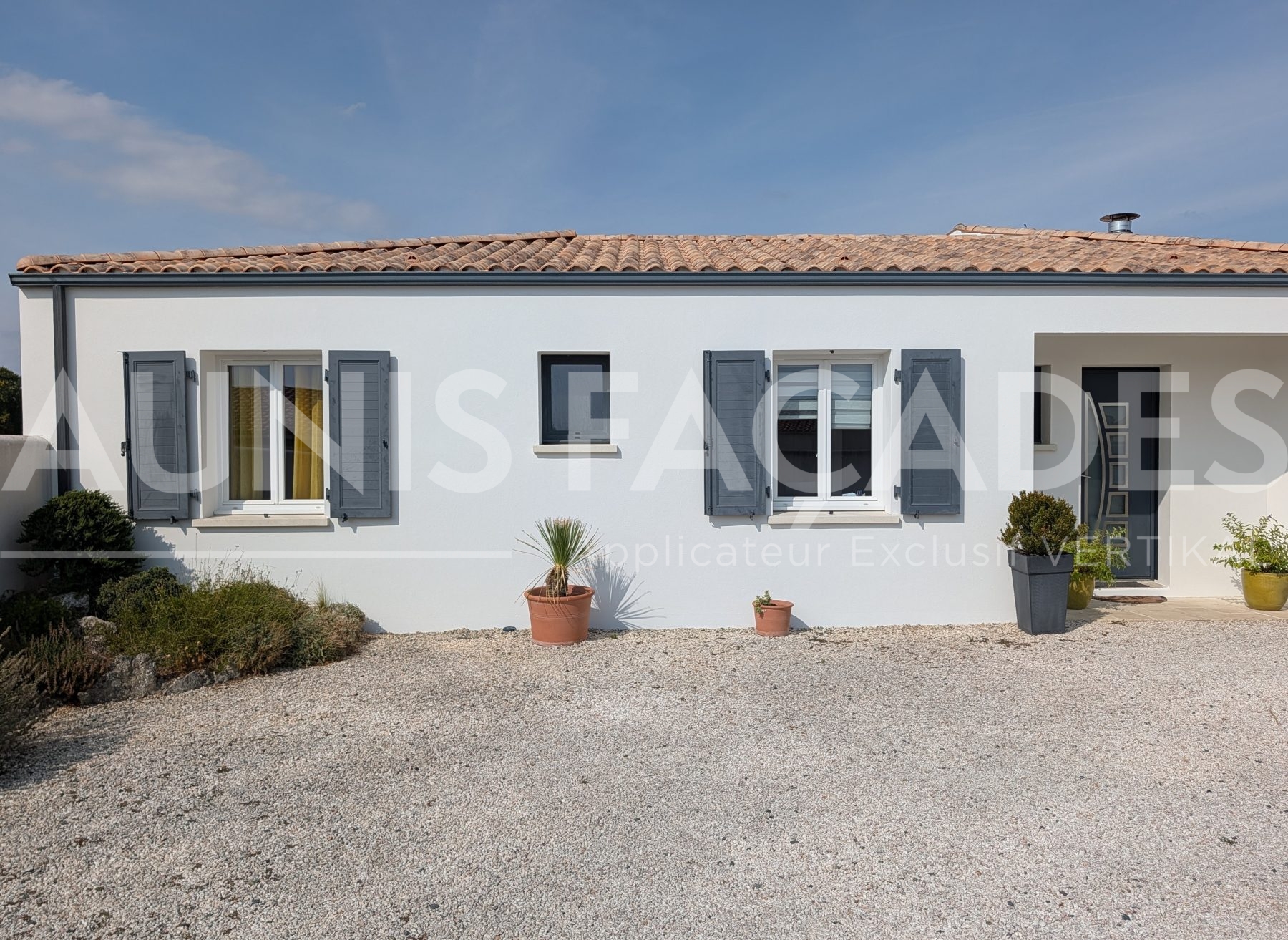 Façade de maison blanche avec volets gris rénovée par Aunis Façades